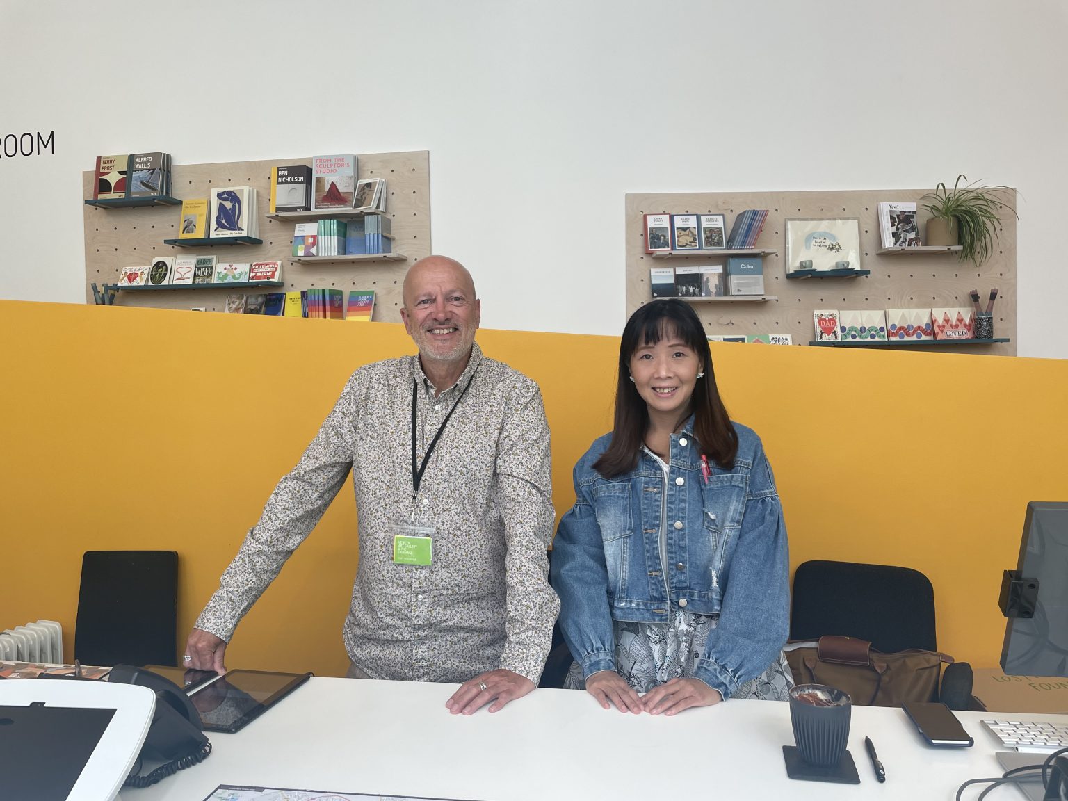 Two smiling volunteers on the front desk, ready to welcome visitors 