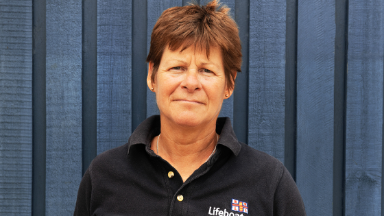 Image of Lifeboat Volunteer Manager, smiling in front of a lifeboat station.