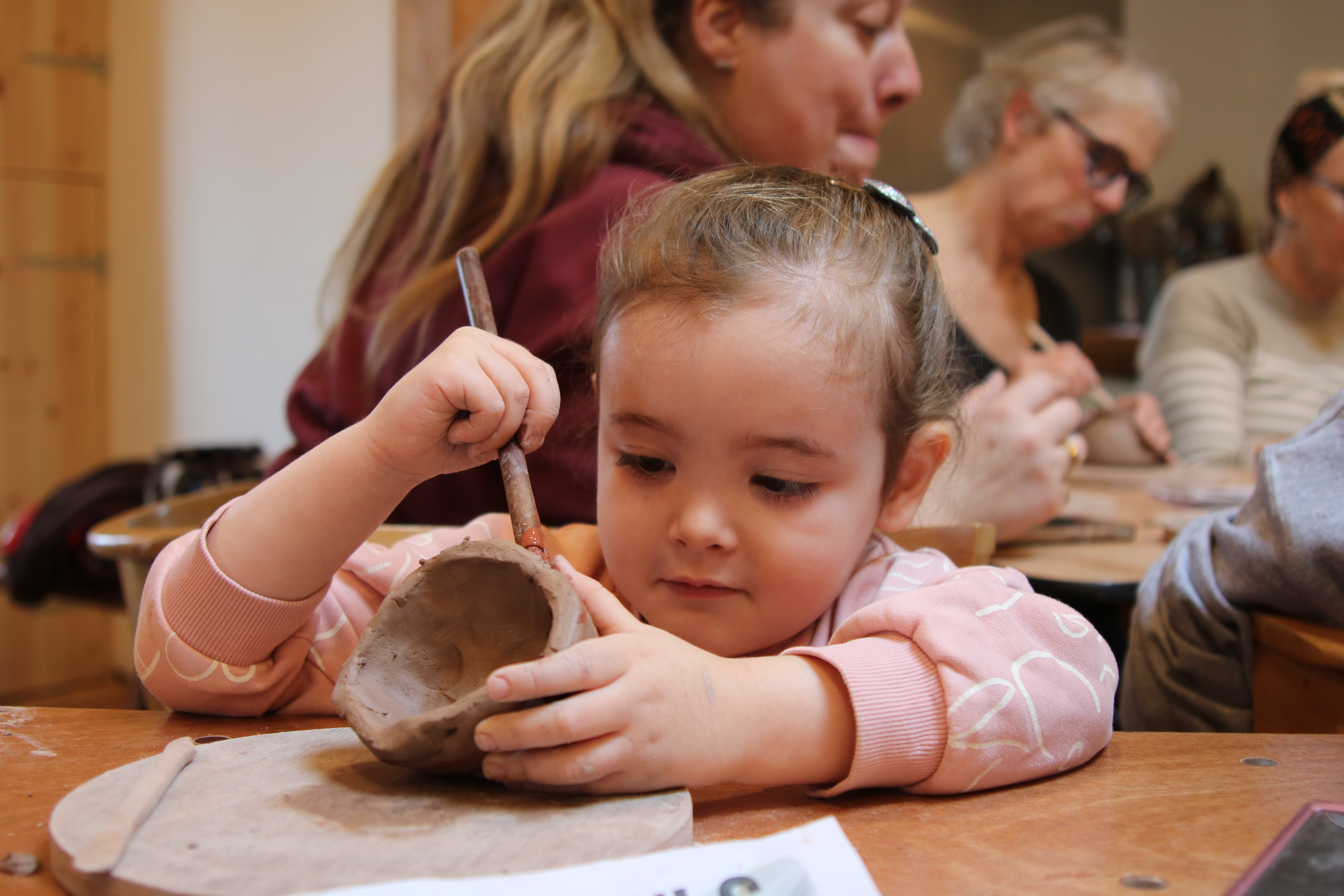 A child in a pink jumper decorates egg cups as part of a family workshop