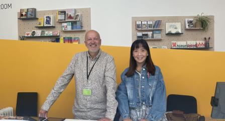 Two smiling volunteers on the front desk, ready to welcome visitors 