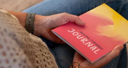 Woman reading a booklet entitled Moving Forward