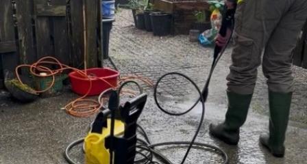 Person in High visibility vest jet washing the ground